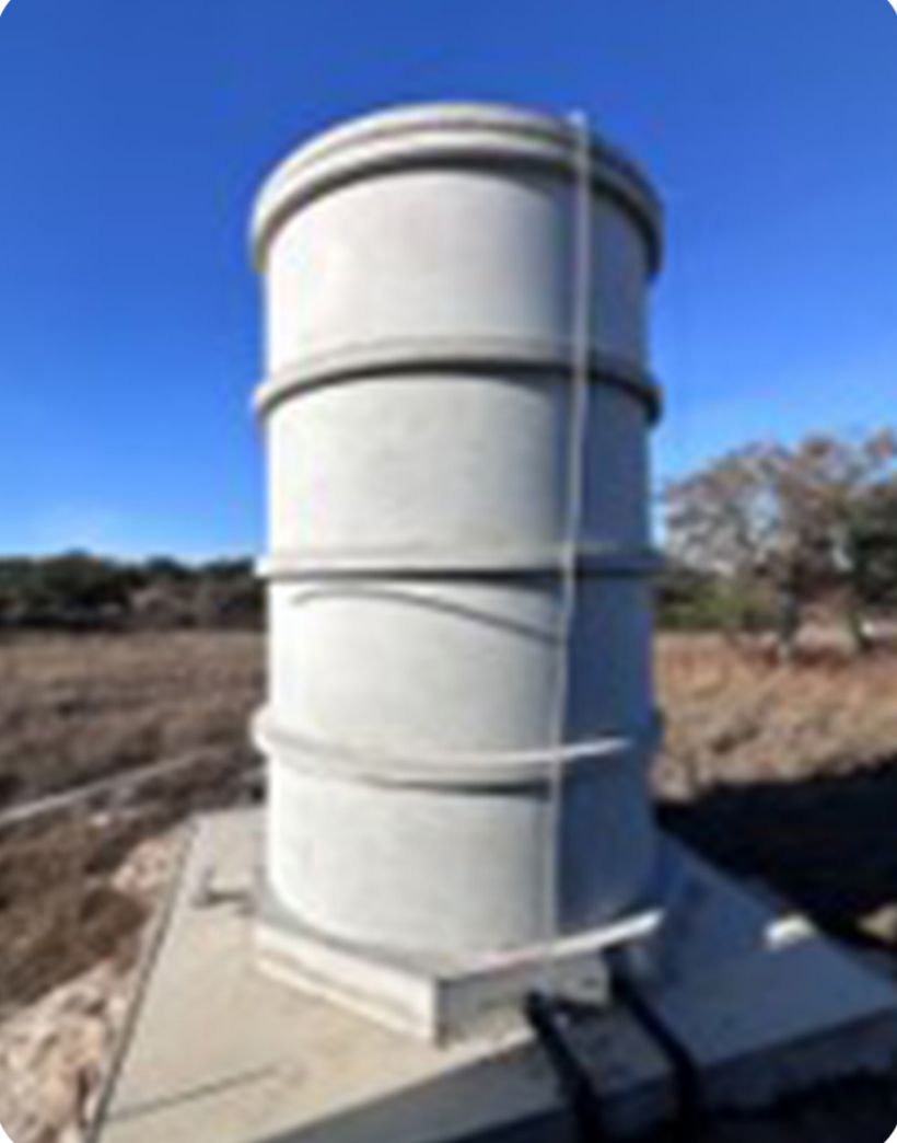 A ringed concrete water storage tank on a Hill Country property