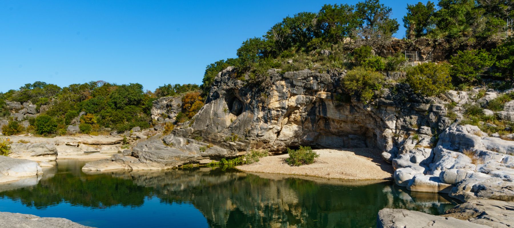 Rocky cliffs and calm river water at Blanco State Park in Texas