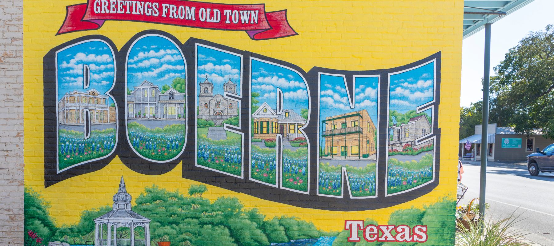 olorful mural reading “Greetings from Old Town Boerne Texas” painted on a brick wall