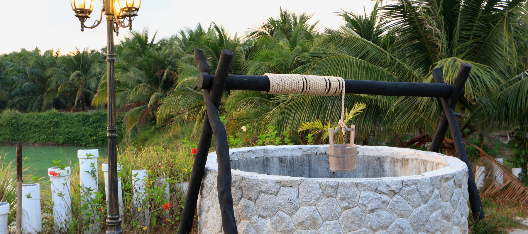 a stone well with a bucket around nice trees