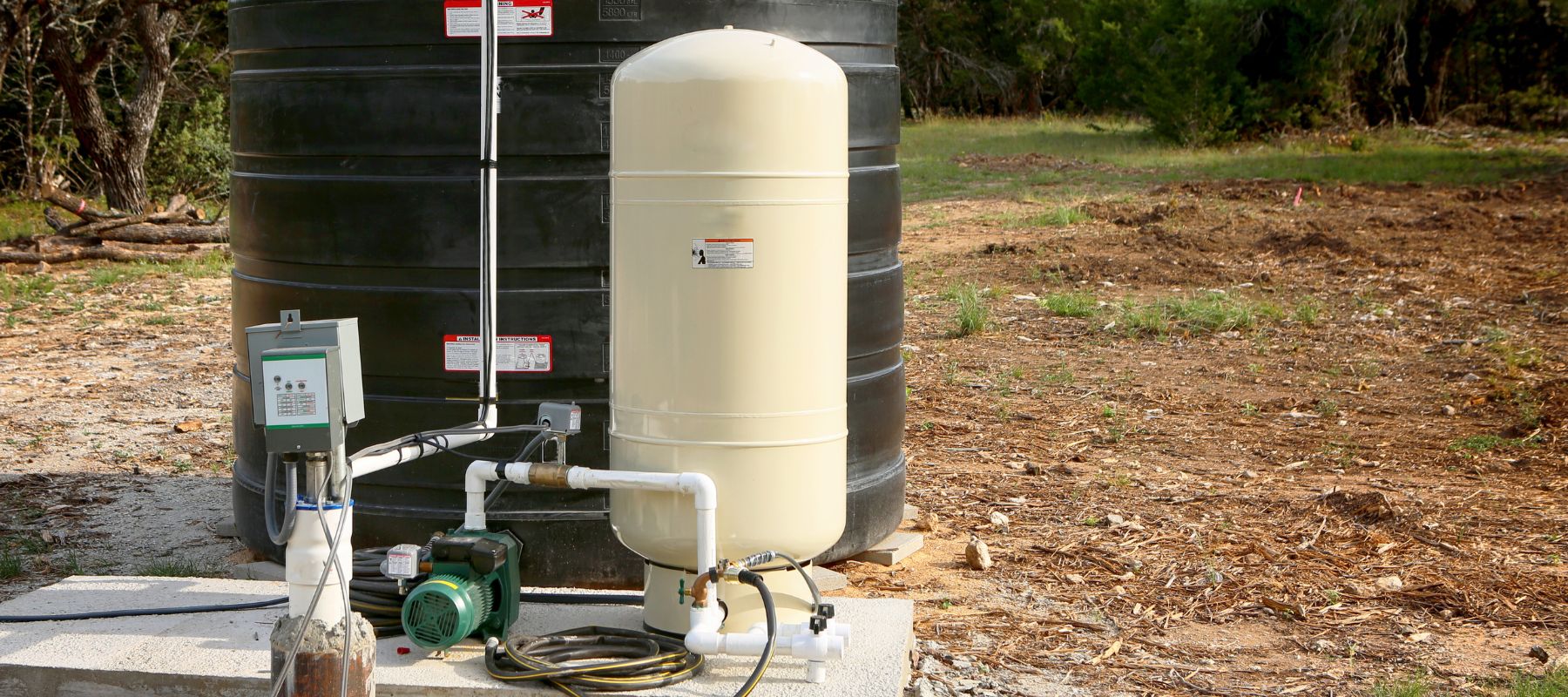 Residential water storage tank and pump system installed outdoors on a concrete pad