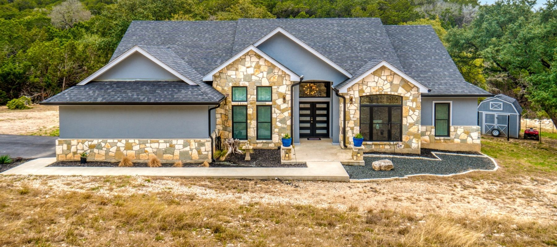 Modern Hill Country–style home with stone exterior and dark shingle roof