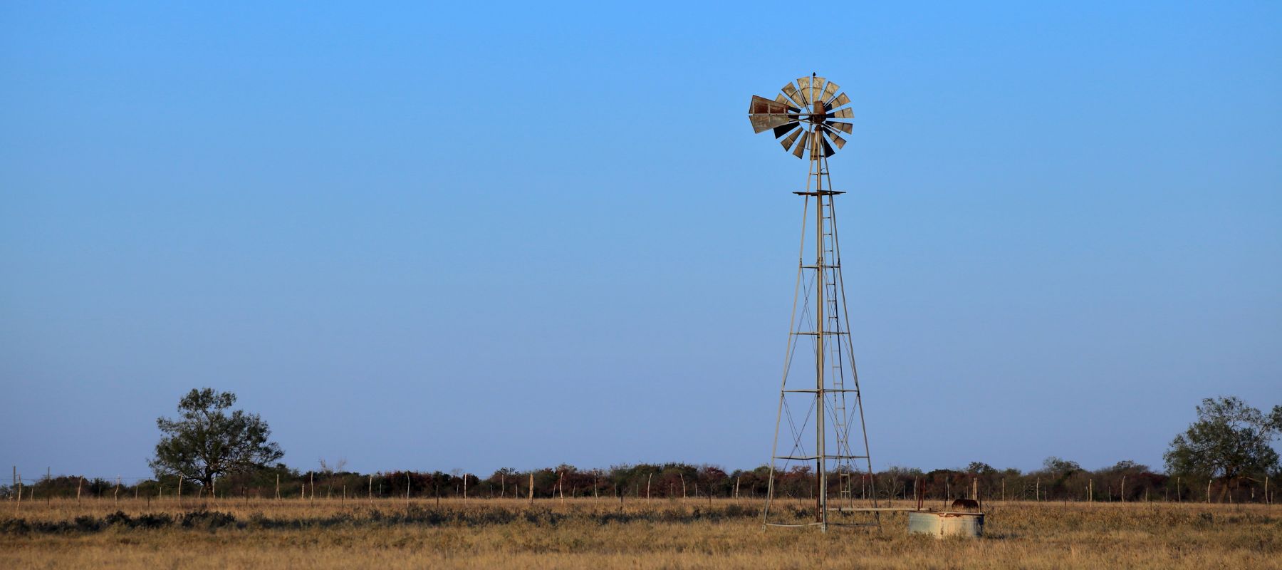 Rural Texas windmill standing in an open field under a clear blue sky in Hondo