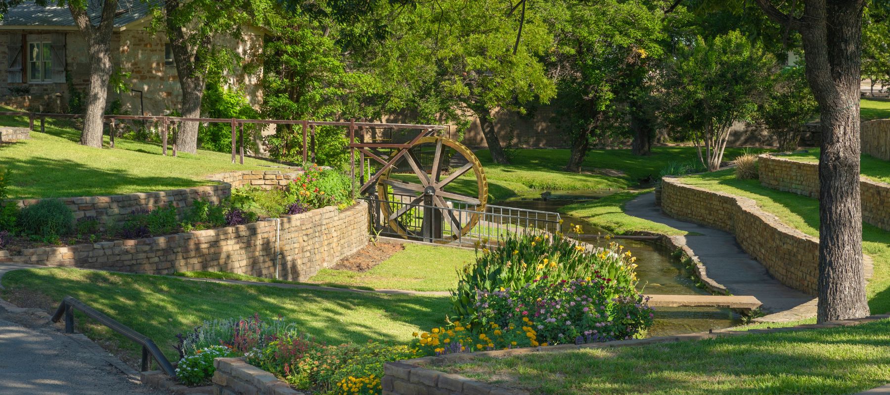 Park with stone pathways, water feature and wooden water wheel